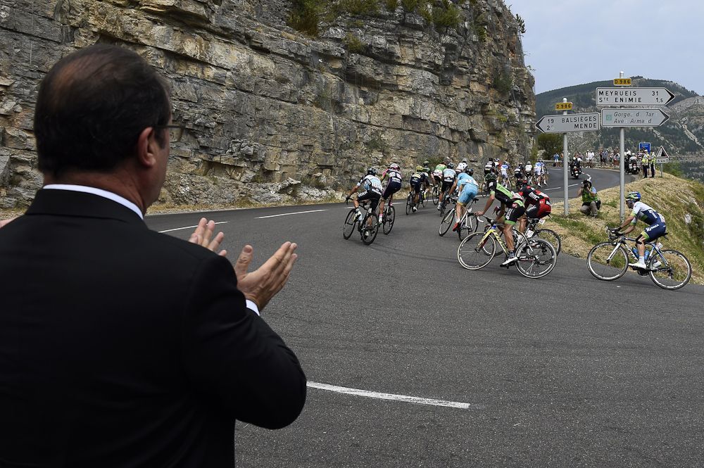 French President Francois Hollande claps as the peloton passes during stage 14 of the Tour de France.