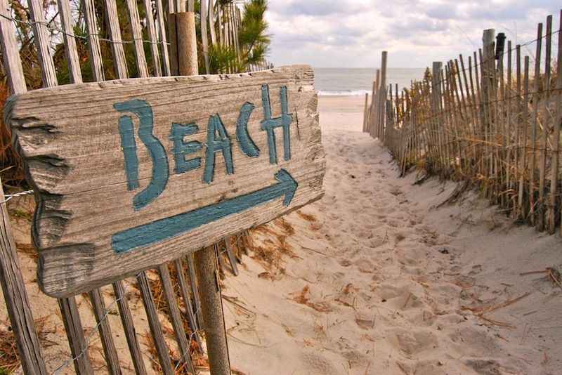 A wooden sign points the way to a beach.