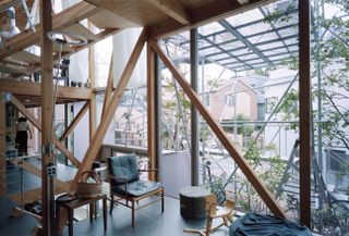 Living space with large openings looking out at naked structure at Daita2019, a Japanese house