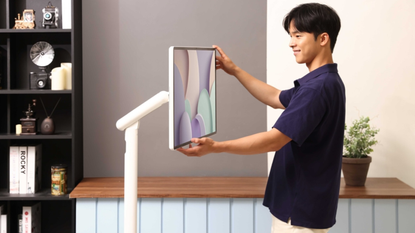 A young man adjusting a Samsung The Movingstyle on its adjustable arm stand