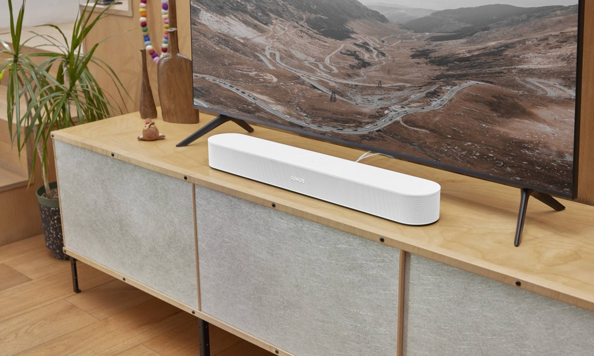 Die Sonos Beam gen 2 Soundbar in Weiß auf einem hölzernen TV-Ständer