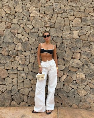 Cass Dimicco wearing black bikini with white pants
