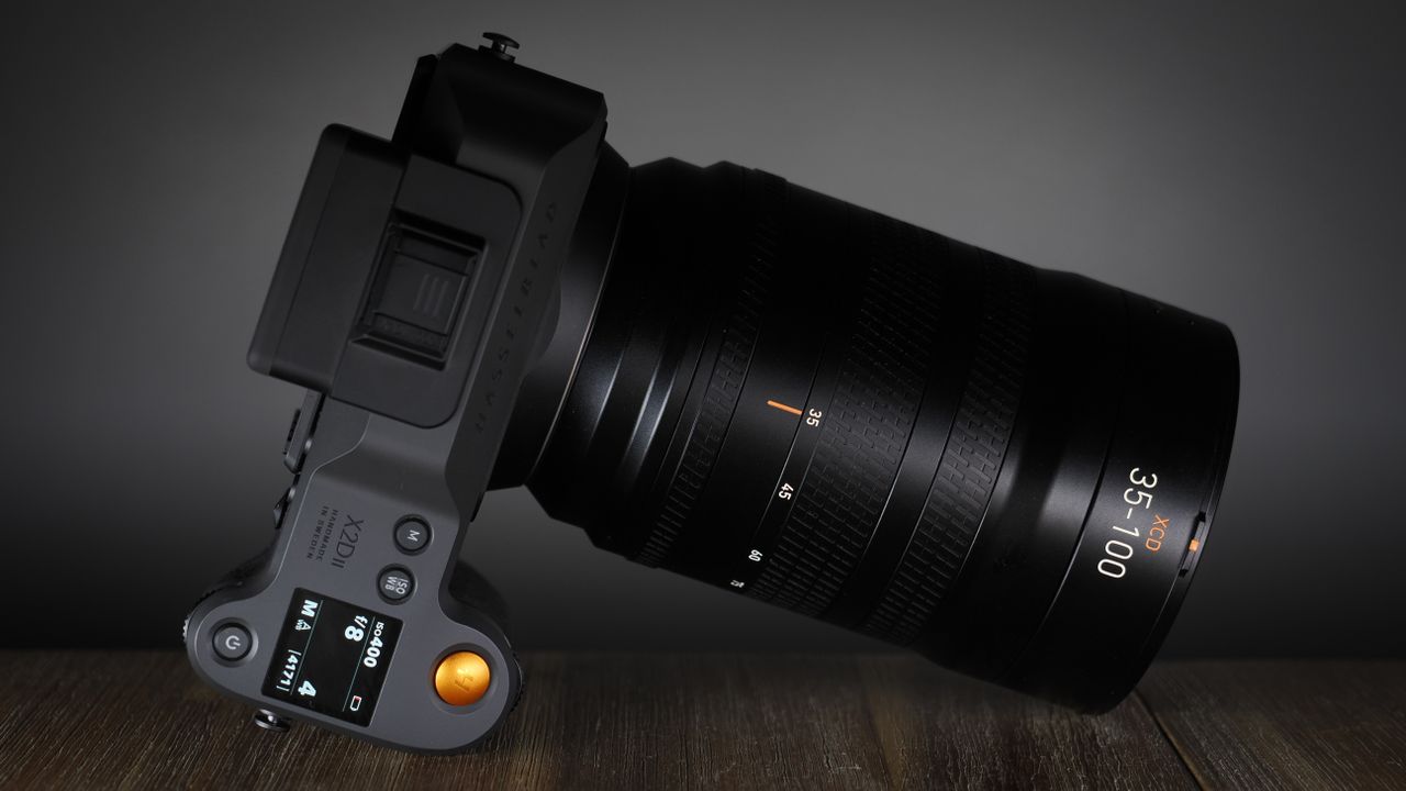 Hasselblad XCD 35-100E lens on a wooden surface in a moodily lit environment