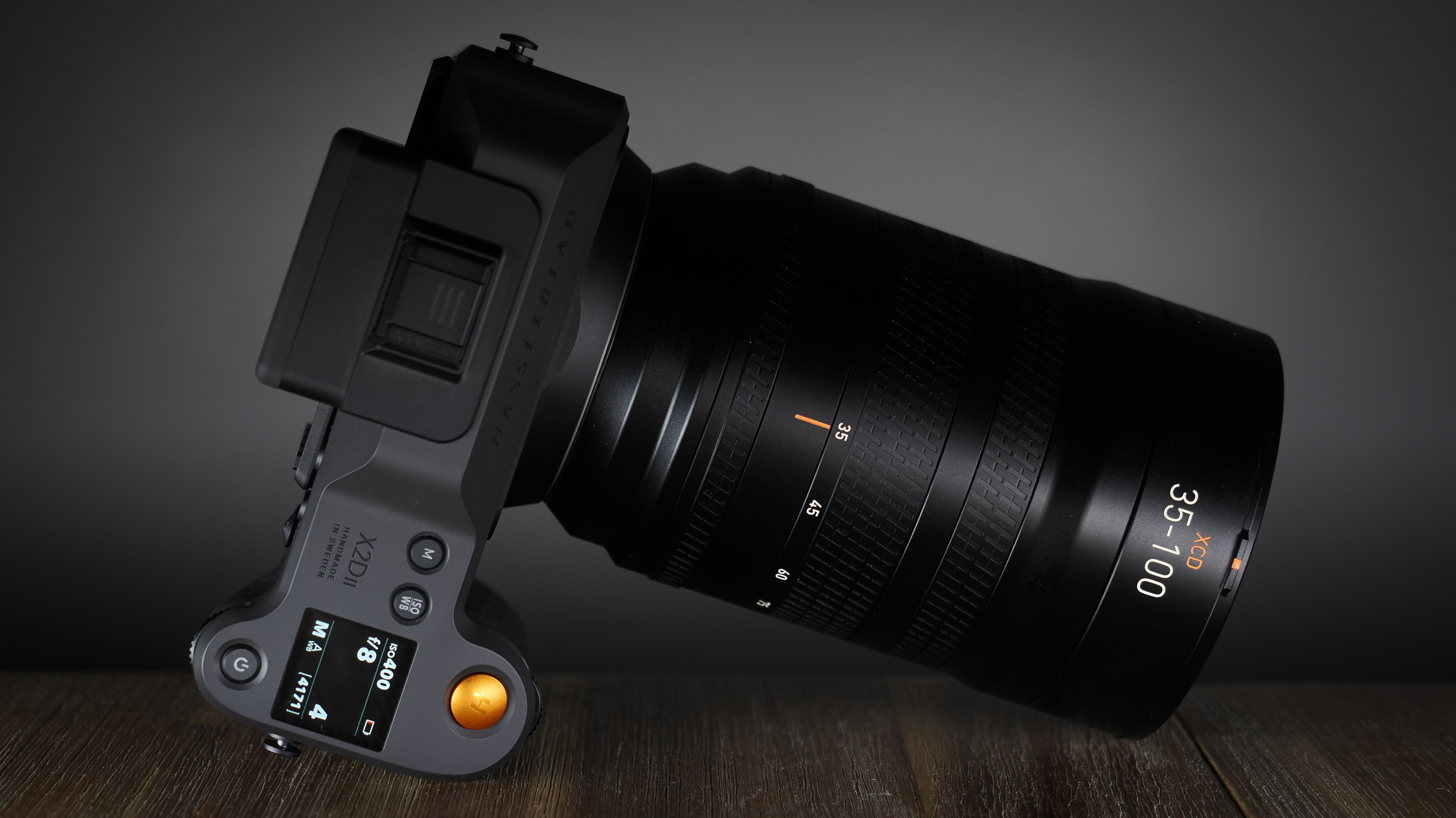 Hasselblad XCD 35-100E lens on a wooden surface in a moodily lit environment