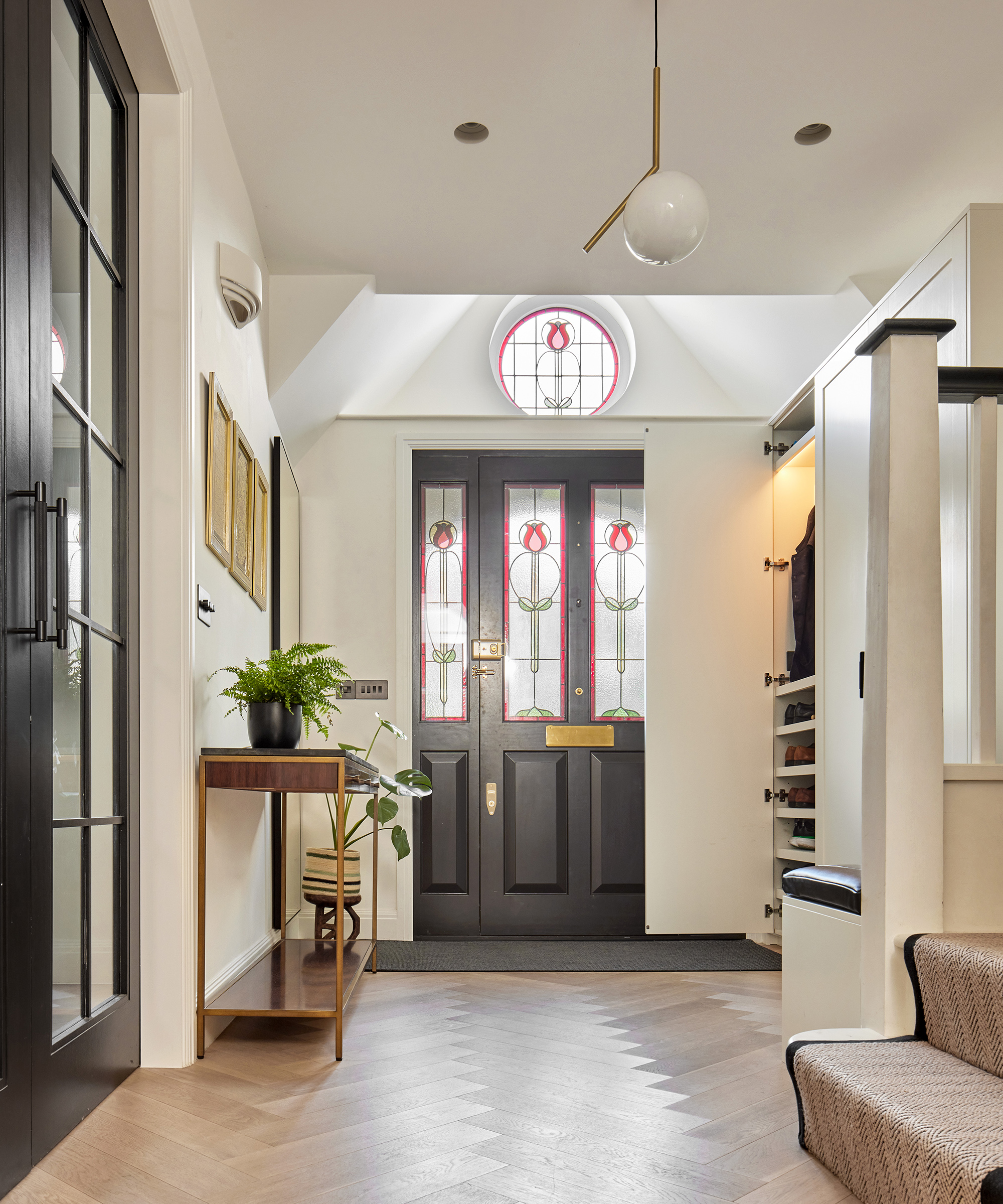 Light oak parquet flooring in a hallway with a black front door with stained glass