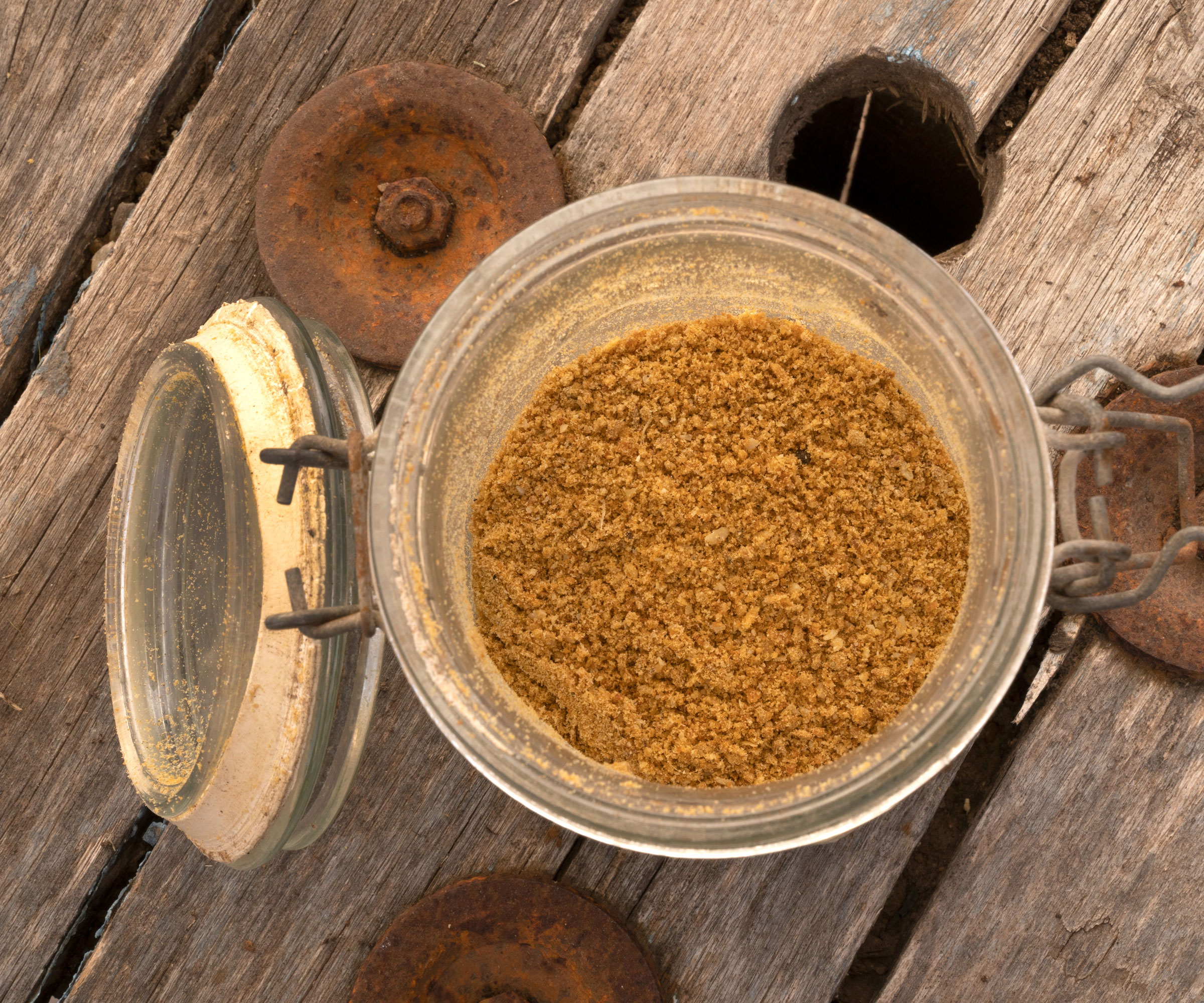 bone meal granules in glass jar on wooden table