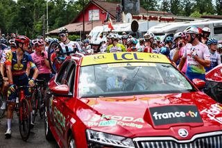 Race Direction vehicles immobilize the pack of riders following a mass crash in the first kilometers of the 14th stage of the 110th edition of the Tour de France cycling race, 152 km between Annemasse and Morzine Les Portes du Soleil, in the French Alps, on July 15, 2023. (Photo by Anne-Christine POUJOULAT / AFP)