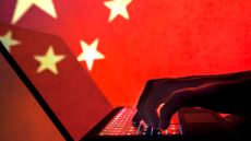 Chinese hacker concept image showing hands typing on keyboard with People's Republic of China flag in background.