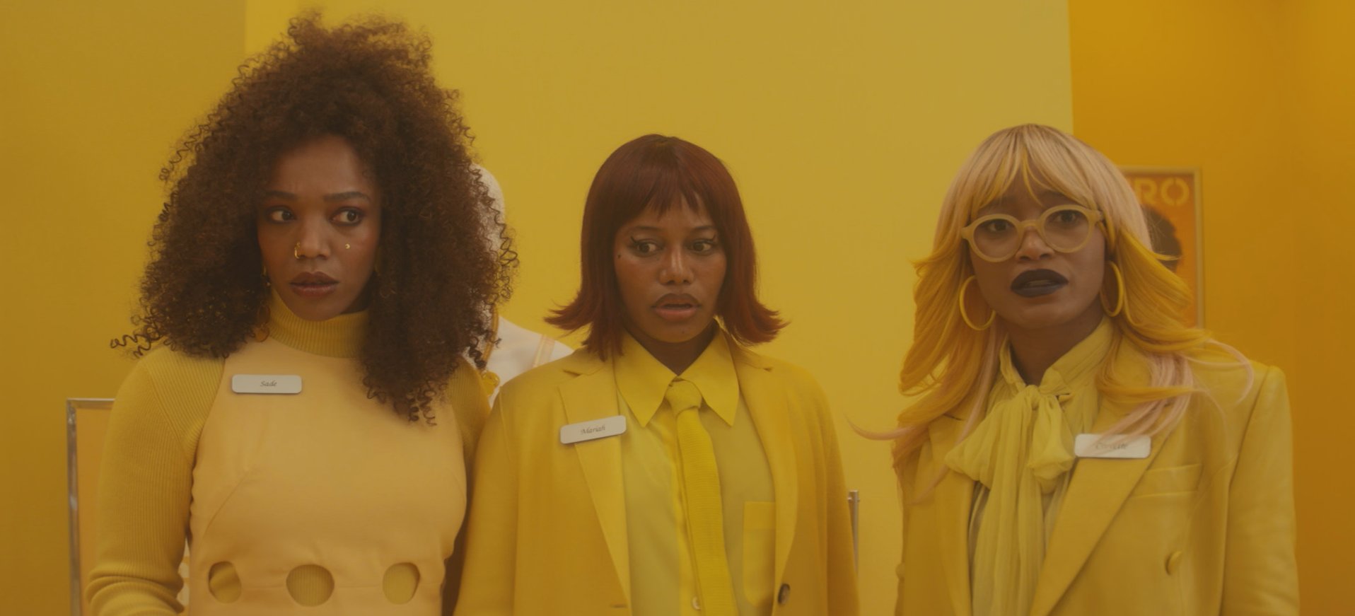 three women played by naomi ackie taylour paige and keke palmer wearing yellow suits in an all yellow room in a still from the movie i love boosters