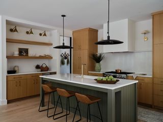 A kitchen with green island and brown cabinets