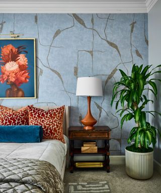 sumptuous bedroom with blue and gold wallpaper and artwork