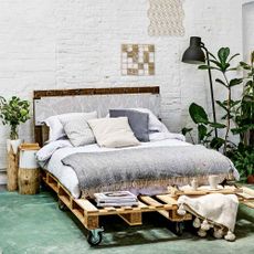 room with white wall and wooden pallet bed 