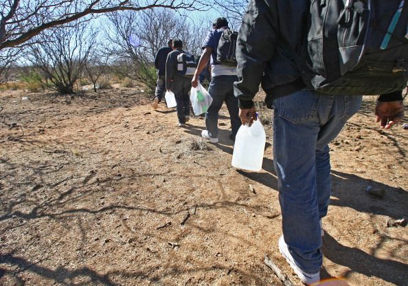 Migrants with water walk through the Arizona desert. 