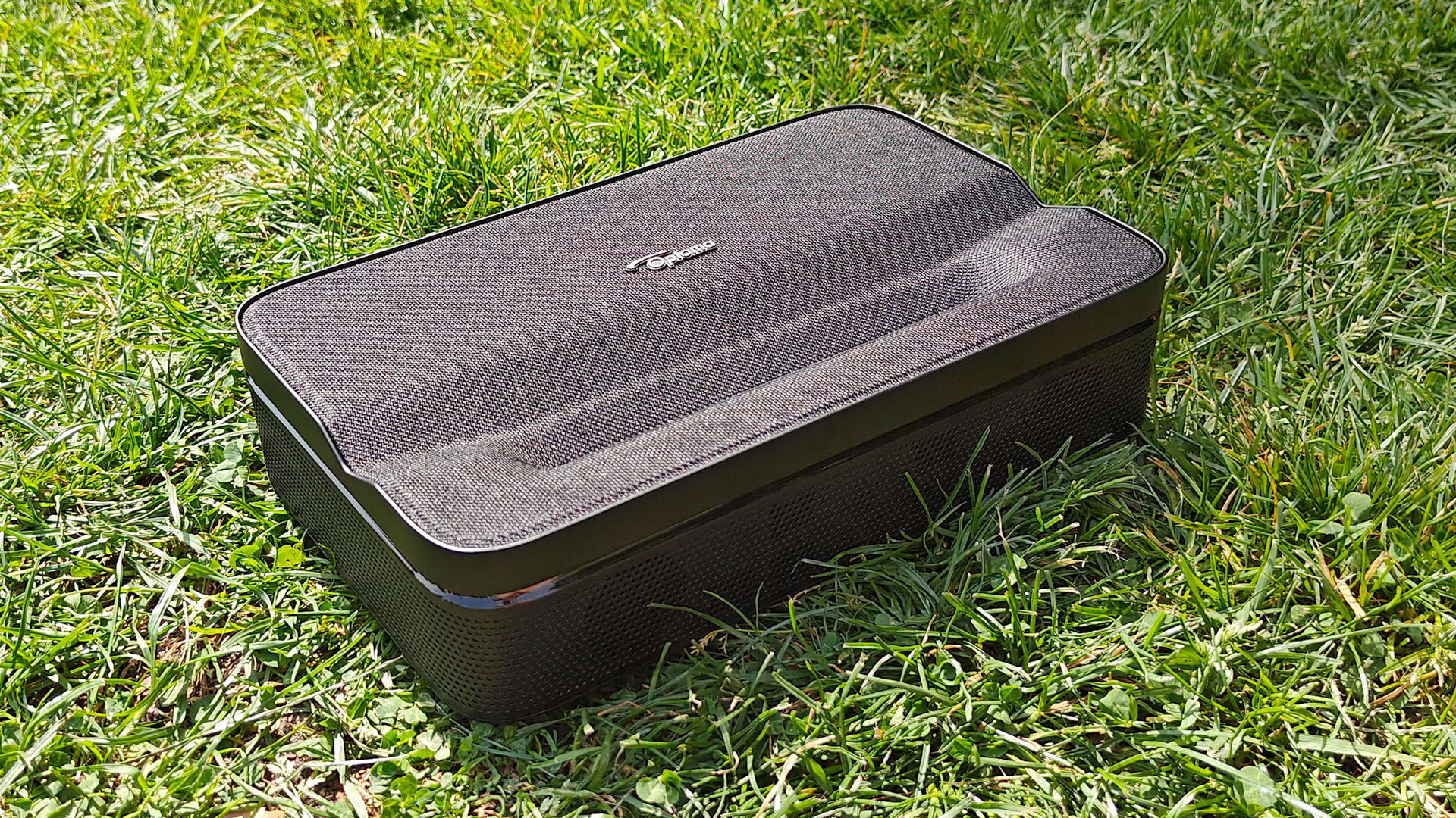 Optoma Photon Go portable UST projector sitting on grassy lawn slight top down view