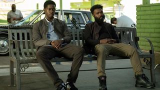 Damson Idris as Franklin Saint and Damien D. Smith as Top Notch sitting on a bench in Snowfall season 6