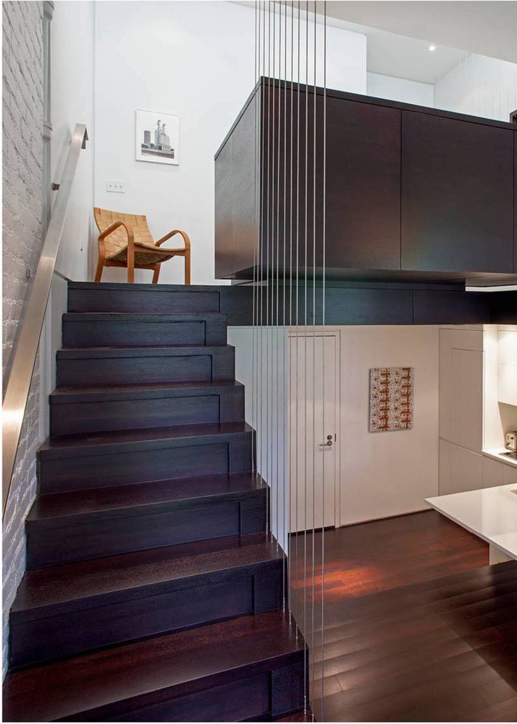 A set of wooden stairs leading to a mezzanine level with a woven chair at the top