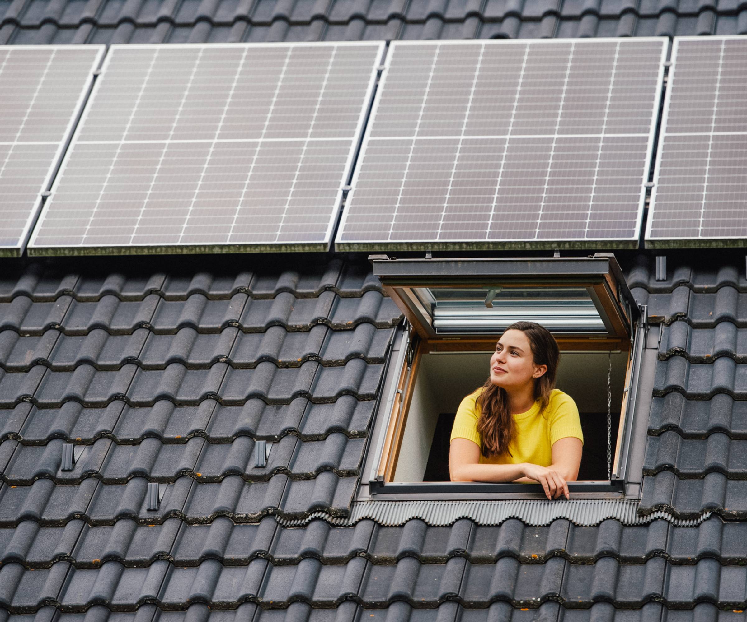woman looking out of rooflight with solar panels on roof above her