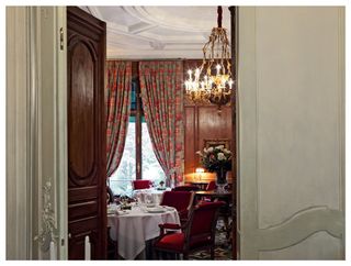 Opulent dining room seen through open door at Le Clarence restaurant, Paris