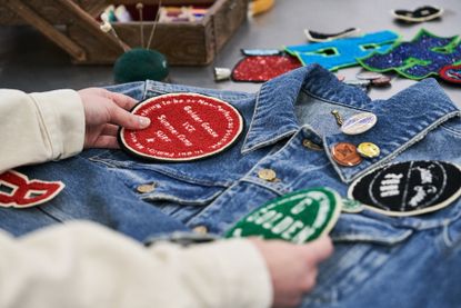 Man putting Golden Goose patches on denim jacket