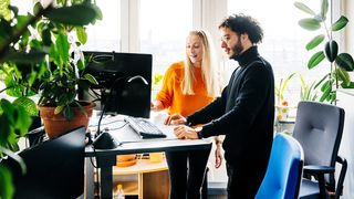 best standing desks: two people standing by an office desk