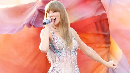 Taylor Swift performs against a multicolored background