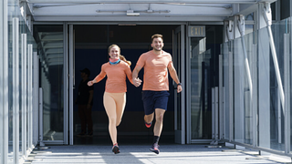 Wife and husband Alyssa Borden and Josiah Borden running through a station in The Amazing Race season 37