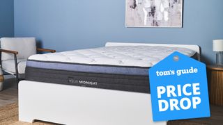 Image shows the Helix Midnight Luxe mattress on a white wooden bedframe in a bedroom designed with blue walls, and with a blue Tom's Guide price drop sales badge overlaid on the image in the bottom right hand corner