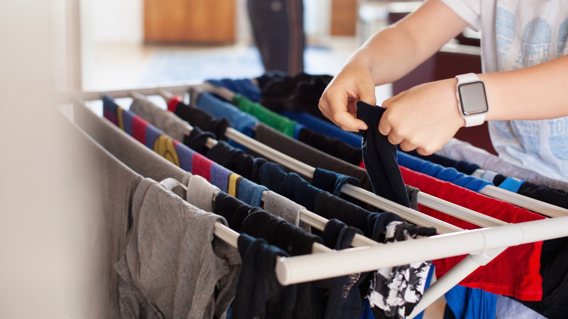 person hanging clothes up on a heated clothes airer
