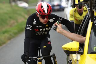 Team Visma-Lease a Bike's Danish rider Jonas Vingegaard (L) grabs an enegry gel from his team's car after falling during the 5th stage of the Paris-Nice cycling race, 196,5 km between Saint-Just-en-Chevalet and La CÃ´te-Saint-AndrÃ©, on March 13, 2025. (Photo by Anne-Christine POUJOULAT / AFP)