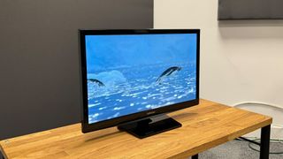 Samsung UE24N4300 TV from side angle on wooden bench showing penguins on screen