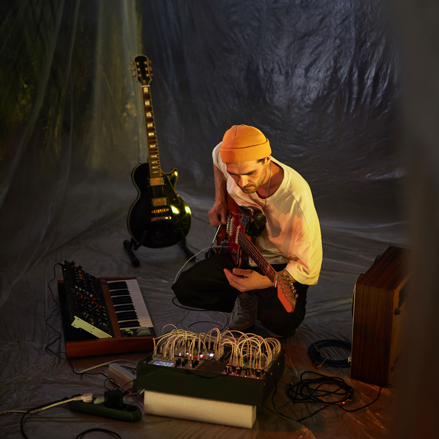 A guitarist looks at a modular synth unit, full of cables