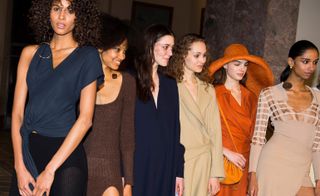 Models wear V-neck T-shirts in navy, others wear chunky knitwear and bright coloured trench coats