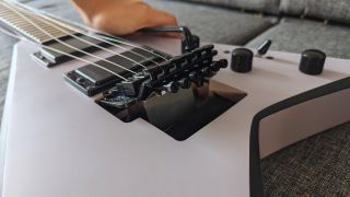 A man presses down on the whammy bar of a Floyd Rose tremolo on the Jackson X Series Rhoads RRX24