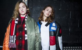 2 models wearing red checked shirt and green casual jacket and white sweatshirt with blue, red and white leather jacket