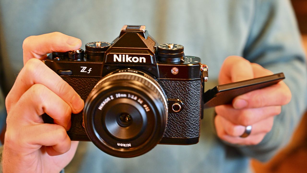 Nikon Zf camera in the hand with vari-angle screen out to the side and with Z 28mm F2.8 SE lens attached