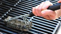 Grill grates being cleaned with a grill brush