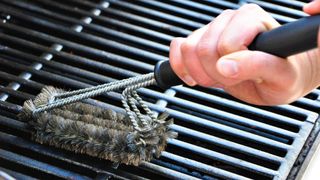 Grill grates being cleaned with a grill brush