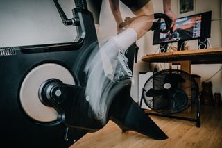 Male cyclist pedalling at a high cycling cadence indoors on a smart bike