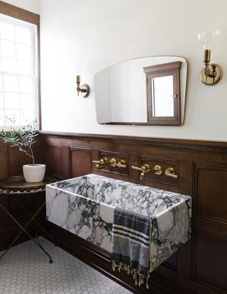 A bathroom with a wooden wainscot as a backdrop to a clean-lined stone sink