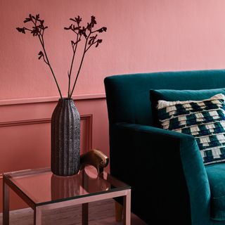 Red clay painted living room wall behind blue velvet sofa