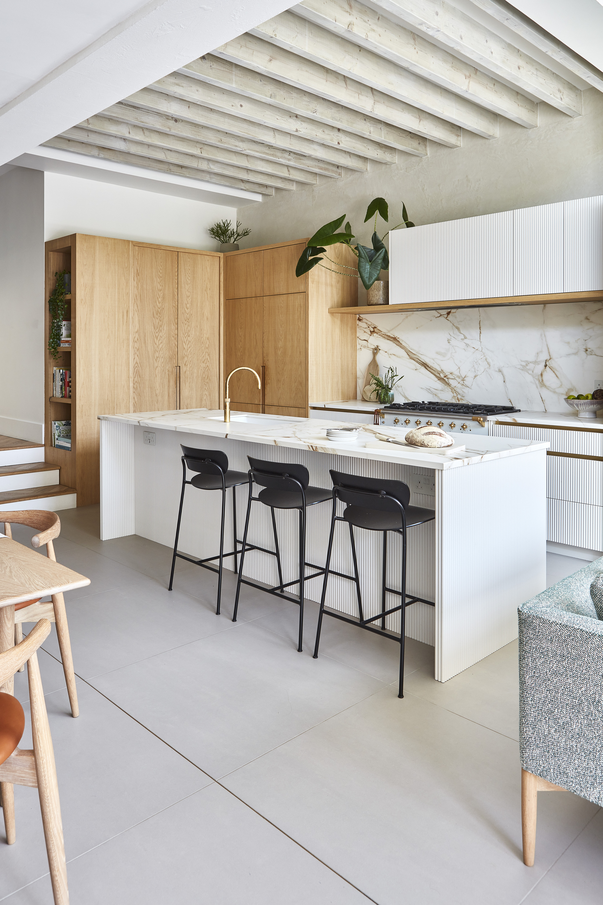 A modern kitchen with wooden cabinets, marble countertops, and gray slab tile flooring
