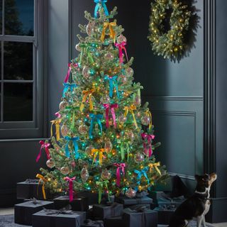 Bright Christmas tree with yellow, pink, blue and green ribbons, bright lights, black wrapped presents