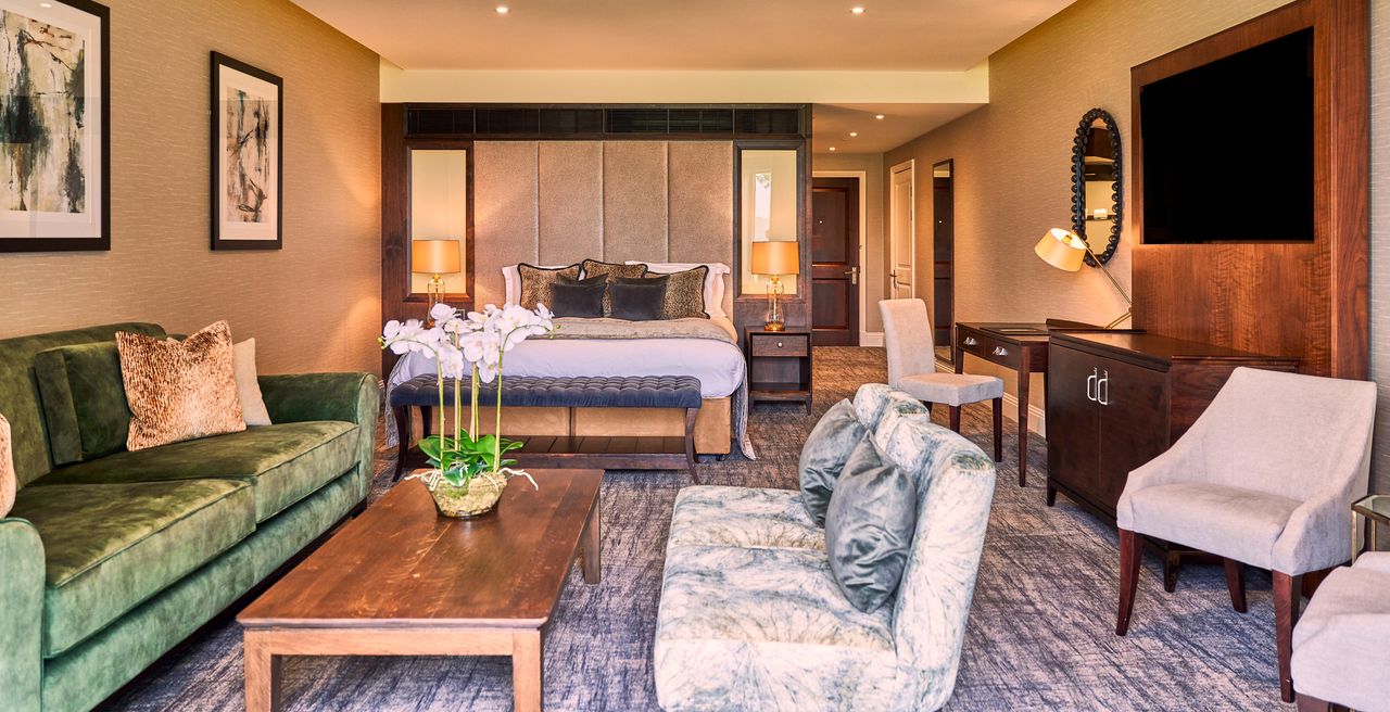 A hotel room with two sofas and coffee table and a bed up against the wall