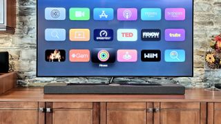 KEF XIO soundbar on TV stand with TV