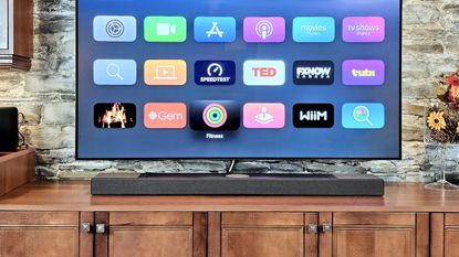 KEF XIO soundbar on TV stand with TV