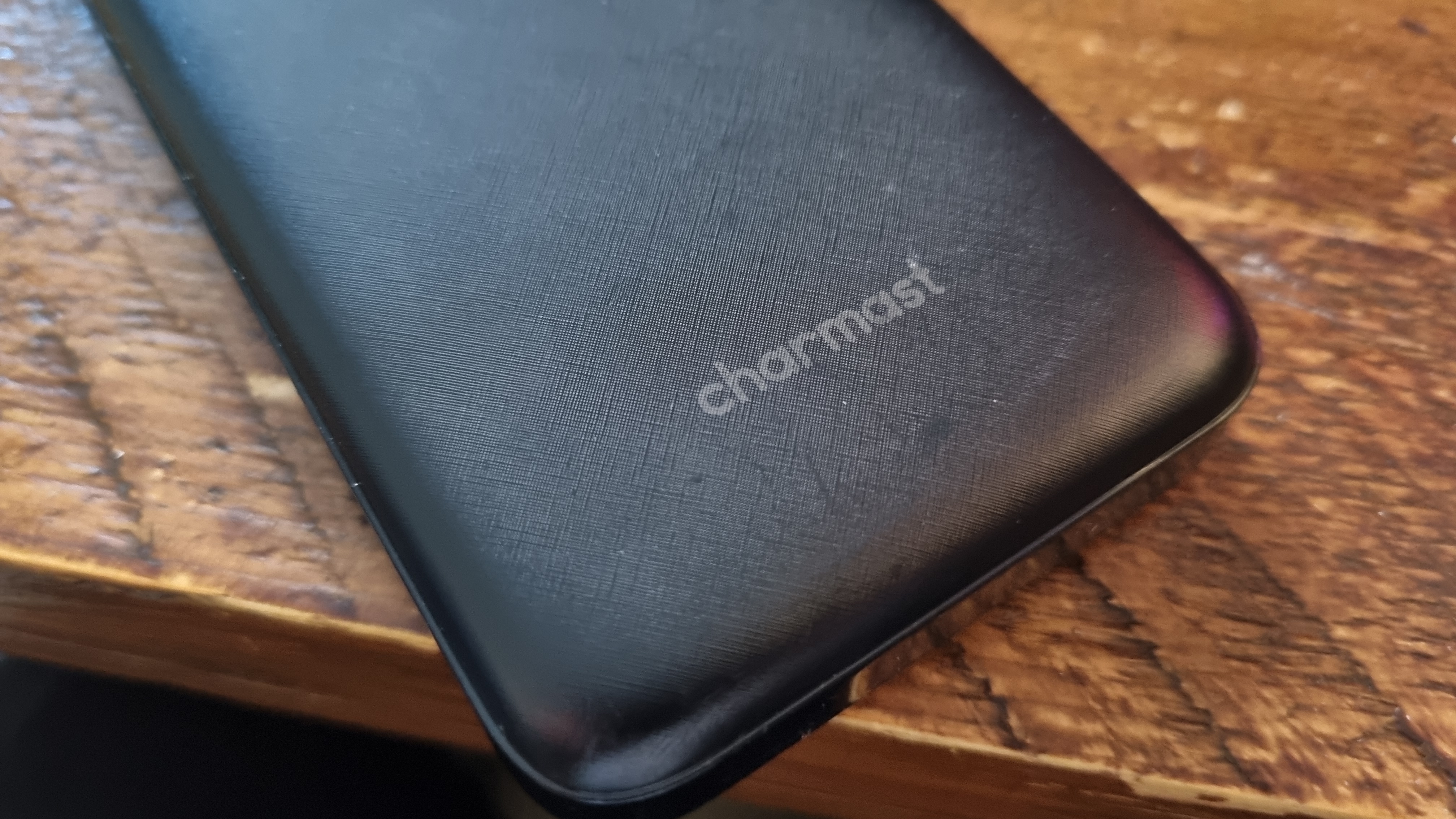 A Charmast portable power bank on a wooden desk