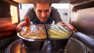 Man taking ready meal out of microwave
