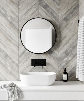 circular bathroom mirror against grey tiles
