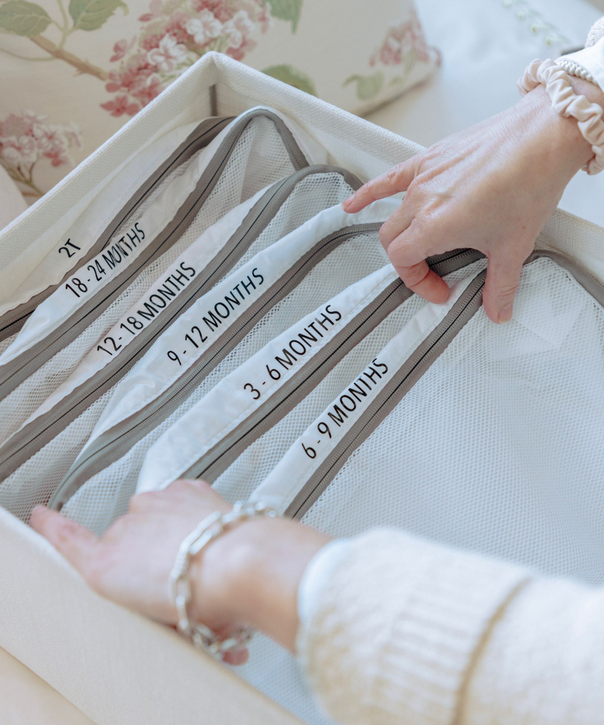 A lady's hands putting labelled packing cubes in a container.