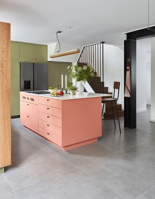 a kitchen with a coral island and green cabinets